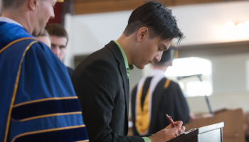 A student signs the register at Matriculation